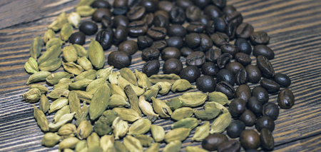 Whole grains of coffee and cardamom together on a table.の写真素材