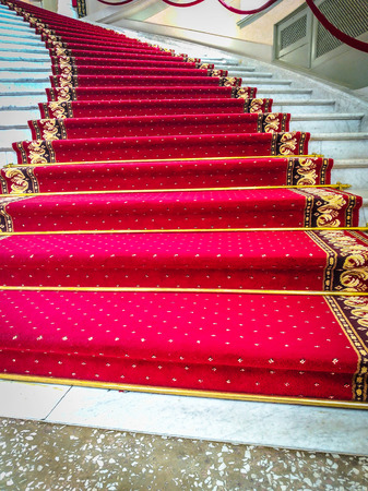 Beautiful curved staircase with red carpet for guestsの写真素材
