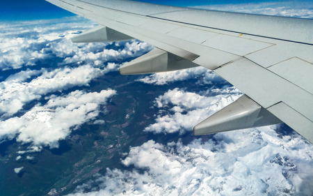 Mountains and white snow on the tops under the wing of the aircraft during the flight.の写真素材
