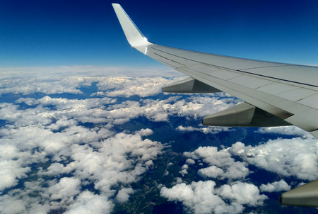 Mountains and white snow on the tops under the wing of the aircraft during the flight.の写真素材
