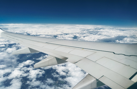 Mountains and white snow on the tops under the wing of the aircraft during the flight.の写真素材