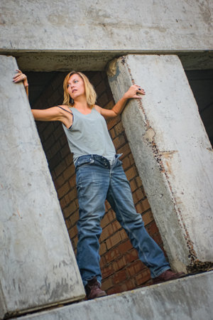 Young woman in rough clothes posing in an abandoned house.の写真素材