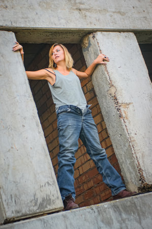 Young woman in rough clothes posing in an abandoned house.の写真素材