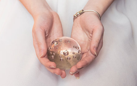 Magic glass ball in the hands of a girl on a light background.の写真素材
