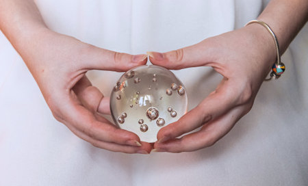 Magic glass ball in the hands of a girl on a light background.の写真素材