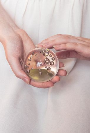 Magic glass ball in the hands of a girl on a light background.の写真素材