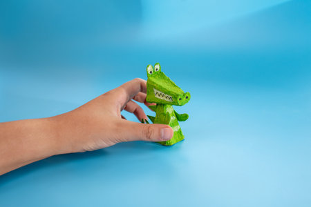 easy paper craft for kids, handmade finger toy made from recycled materials. Green crocodile with visible teeth and spikes, eco-friendly and fun. Perfect for childrens art projects and creative play.の写真素材