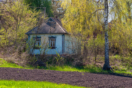 Old abandoned one-storey house in the village. Rural life in Ukraine. Plowed vegetable garden in springのeditorial素材