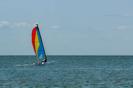 sailboat on the sea. Activities on the water. Sail tricolor red, yellow, blueの写真素材