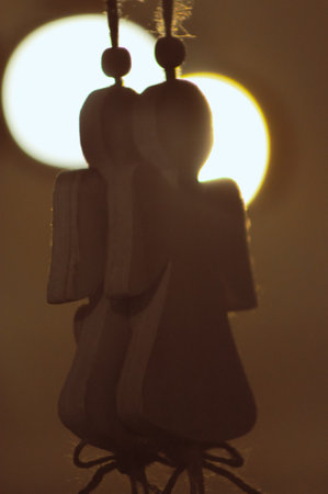 Figures of Christmas angels made of wood on a rope. Silhouette on the background of glowing ballsの写真素材
