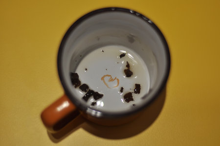 A dirty cup after drinking tea with leaves on the bottom. Orange color of cup and background,...