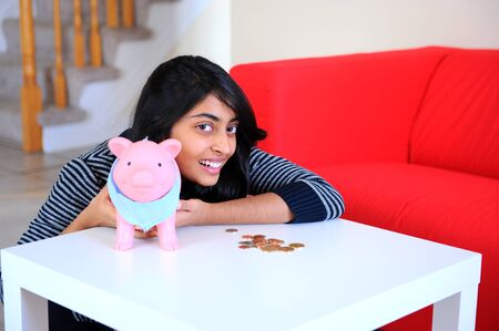 Excite, happy, young Indian girl with her piggybankの写真素材