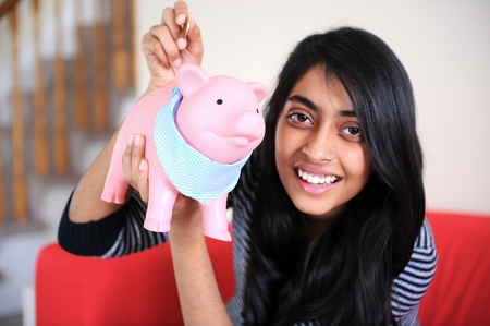 Indian girl holding piggybank and coin for savingの写真素材