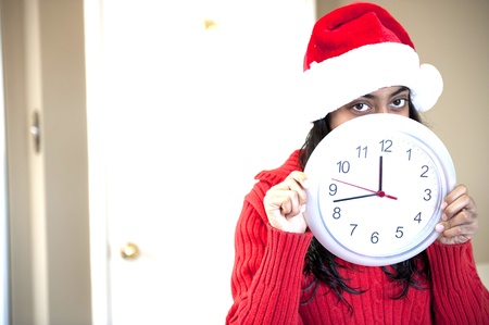 Portrait of happy girl with Christmas cap holding clockshowing time