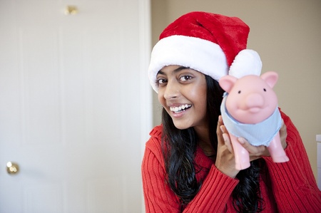 Portrait of happy girl with Christmas cap holdingpiggybank with her savingの写真素材