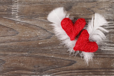 Two red hearts with feathers