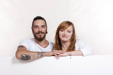 Young urban couple leaning across a white wallの写真素材