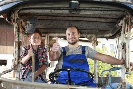 Father and son driving on a tractor on a farm