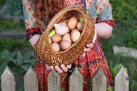 Pretty farm wife with fresh chicken eggs outdoorの写真素材