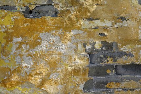 Old yellow wall with brick stonesの写真素材