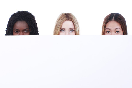 Three different multiracial woman behind a white boardの写真素材