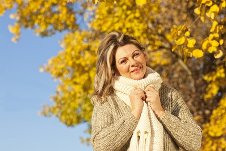 Happy middle aged woman with scarf in fallの写真素材