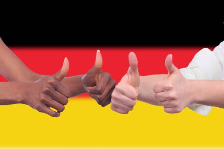 Black and white hands with thumbs up in front of german flagの写真素材