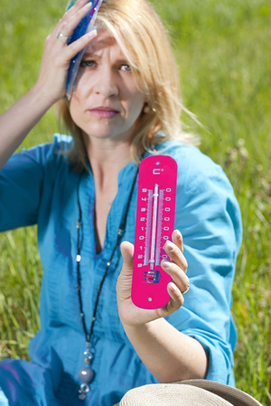 Matured woman with coolpack and thermometer suffering from heatstrokeの写真素材