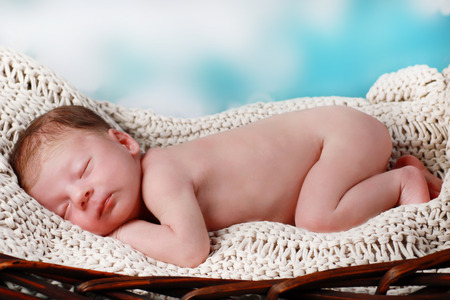 newborn baby with cute hat lying in a fur basket