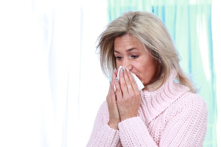 Mature woman uses handkerchief to blow her noseの写真素材
