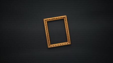 An empty, ornate golden picture frame is positioned at an angle on a dark, textured surface. The frame has a detailed, carved design and a warm golden hue. The background is a deep, muted color, making the frame the central focus of the image.の素材