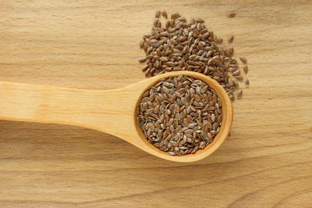 Flax seeds on the wooden plate and wooden spoonの写真素材