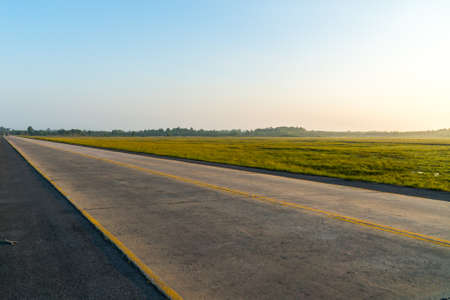 Empty road with blue sky and green field.の写真素材