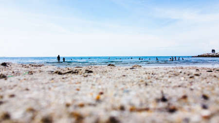 Group of people swimming at the beach with blue sky and close up photo of sand beach.のeditorial素材