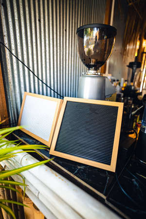 Black and white board in front of Coffee grinder in coffee shop.の写真素材