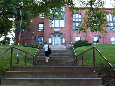 A guy waking up stairs toward college building の素材
