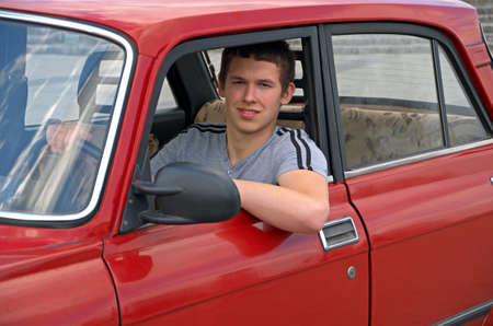 The young man behind the wheel of an old auto 70-80 years of release.の写真素材