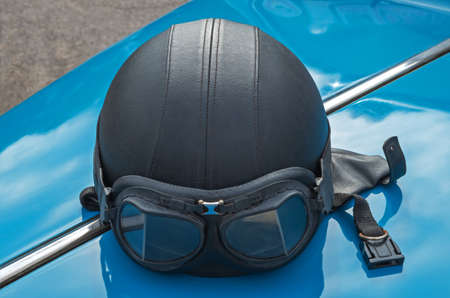 Motorcycle helmet with skin lies on the hood of a retro car.の写真素材