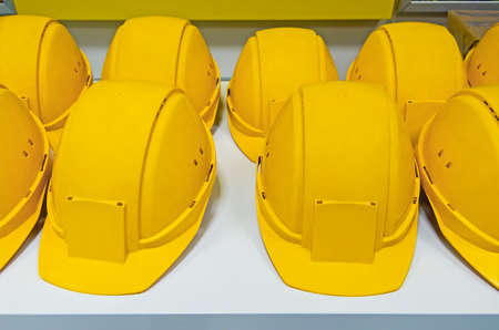 Yellow protecting hard hats on bench ready for workers to pick them.の写真素材