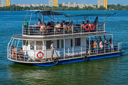 Pleasure boat floating on the water in the city on a background of multi-storey buildings.