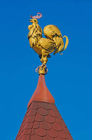 Volume sculpture weathervane in the form of a rooster on the roof of the mansionの写真素材