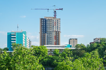 View of a skyscraper under construction from the thickets of a country park