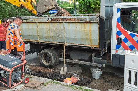 Dnipro, Ukraine - July 31, 2020: Utility workers make preventive repair of storm sewers on city streetのeditorial素材