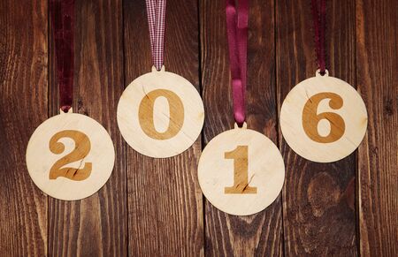 Veneer Christmas balls with numbers 2016 on a rustic wood background
