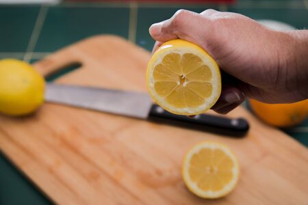 Freshly cut lemon about to be squeezed with a man's handの写真素材