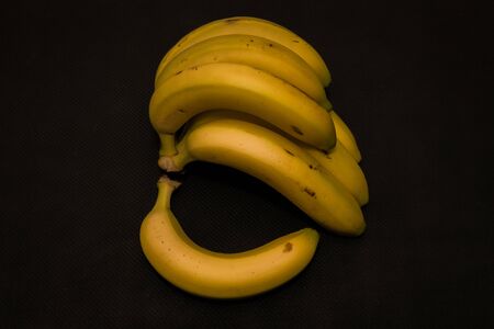 Ripe yellow bananas on dark black groundの写真素材