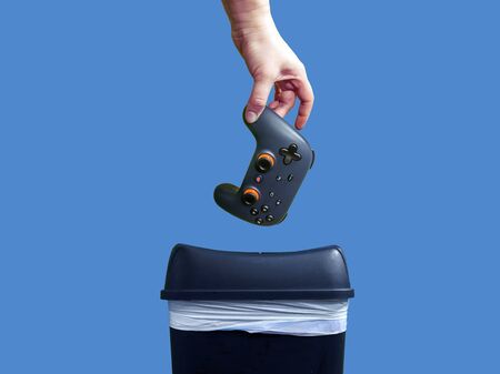 Seattle, WA / USA - circa November 2019: Closeup of a Google Stadia gaming controller being thrown into the trash can in frustration, against a colorful backgroundのeditorial素材