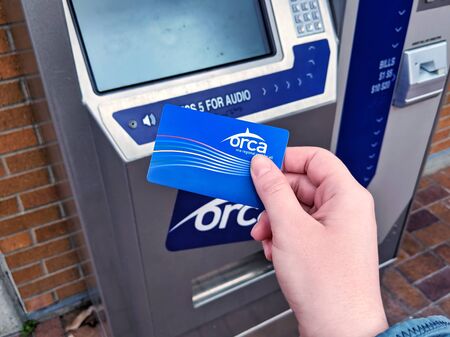 Bellevue, WA / USA - circa December 2019: Person's hand holding a bright blue ORCA transit pass in...