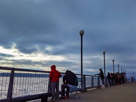 Seattle, WA / USA - circa November 2019: Several people fishing and viewing the landscape from the...