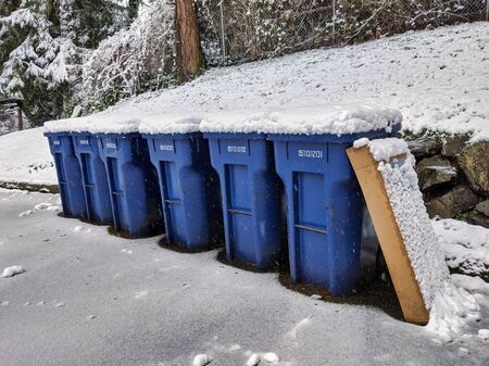 Seattle, WA / USA - circa January 2020: Snow and ice covered blue recycling trash cans in a neighborhood after a heavy snowfall.のeditorial素材